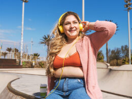 Beautiful woman outdoors listening to music and drinking coffee