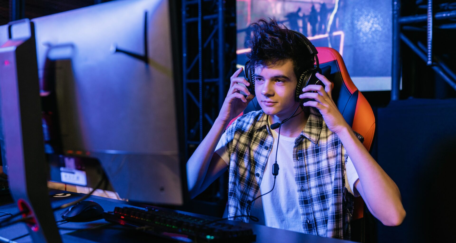 teenager wearing headphones in front of a computer