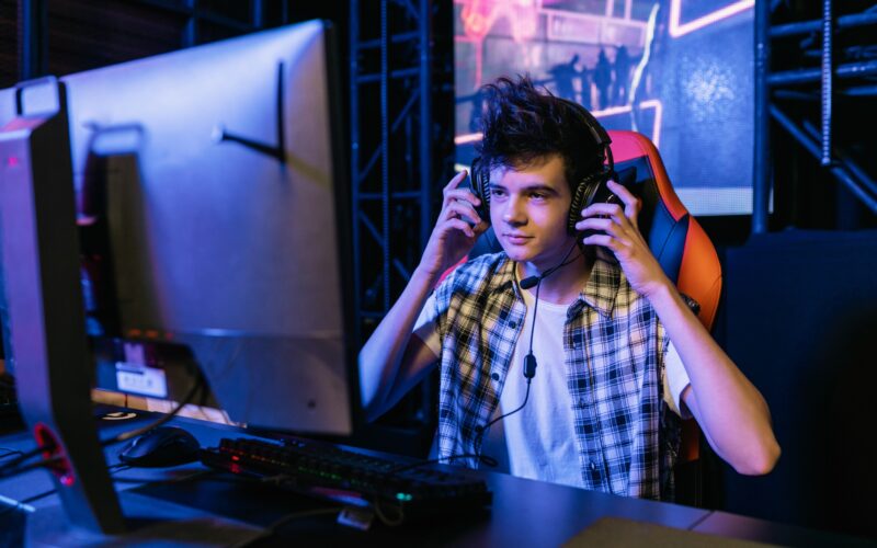 teenager wearing headphones in front of a computer