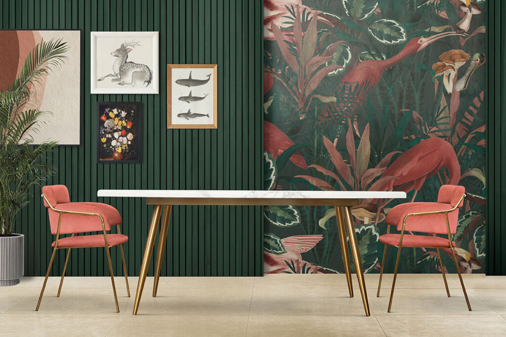 Image of a room that has been curated into a budget-friendly creative home through the use of a fun tropical wallpaper, an accent wall, and  a small image gallery. The color scheme is dark greens and light pinks. There is a leafy house plant and two soft pink chairs with gold accents sitting across from each other. In between the chairs there is a white top table with gold accents.